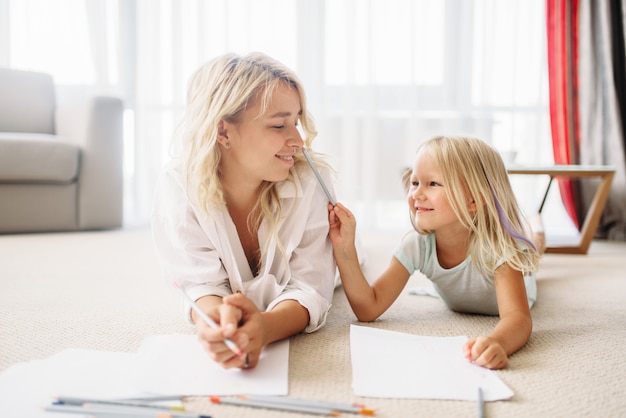 Madre e figlia disegnare sdraiato sul pavimento