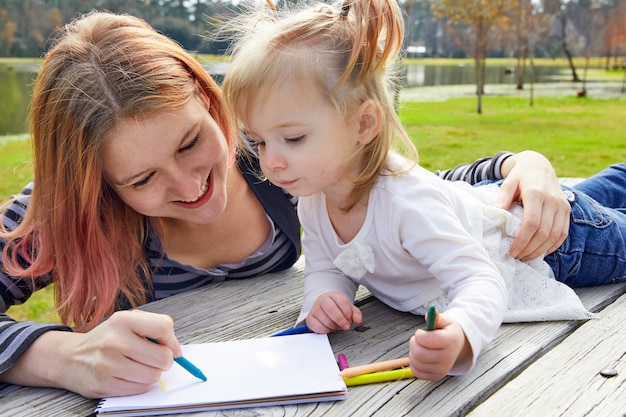 Madre e figlia disegno colori in un parco