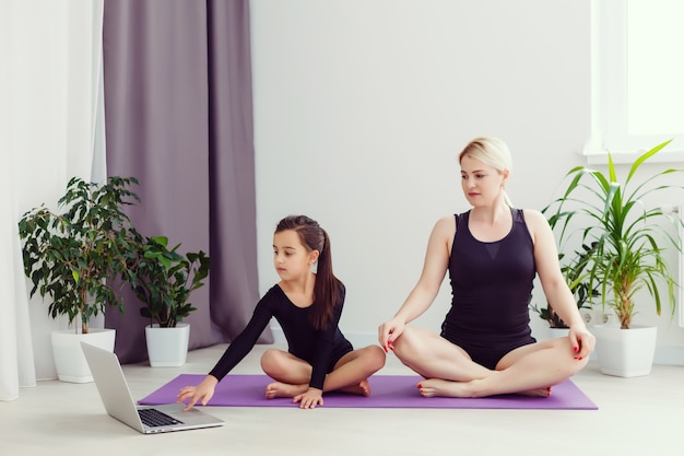 madre e figlia fanno esercizi di yoga online con il laptop a casa