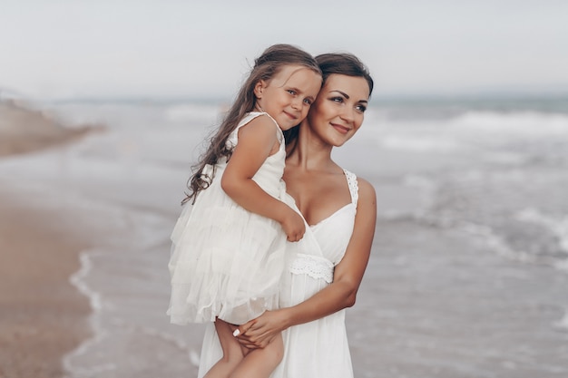 Madre e figlia felici che godono del giorno soleggiato sulla spiaggia