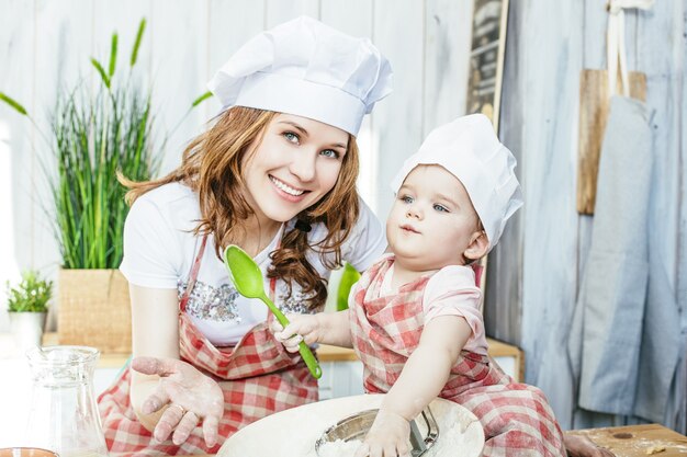 Madre e figlia felici e belle preparano la pasta e la farina in cucina a casa