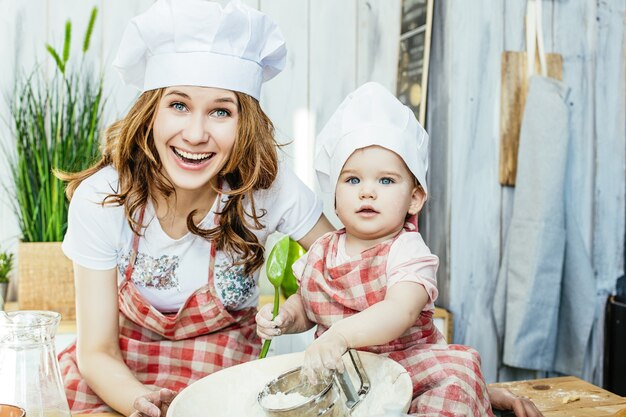 Madre e figlia felici e belle preparano la pasta e la farina nella cucina di casa