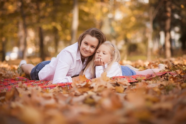 Madre e figlia giacciono nel parco sul fogliame autunnale