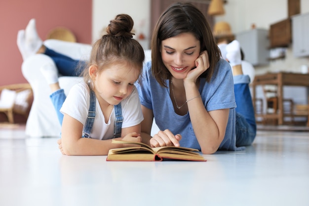 Madre e figlia hanno letto un libro insieme, sdraiate sul pavimento in soggiorno.