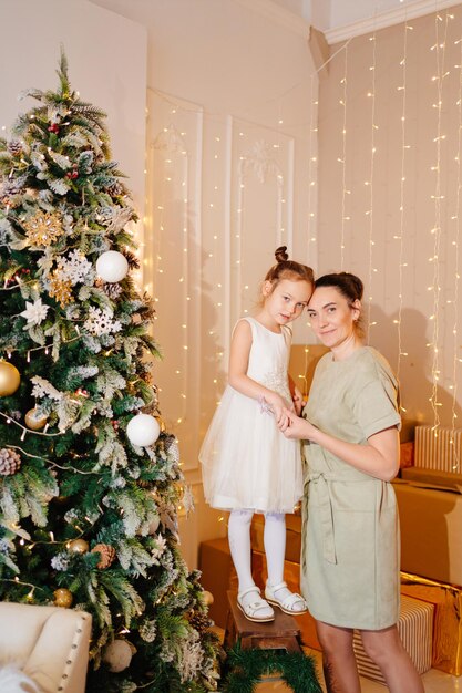Madre e figlia in abito bianco all'albero di Natale
