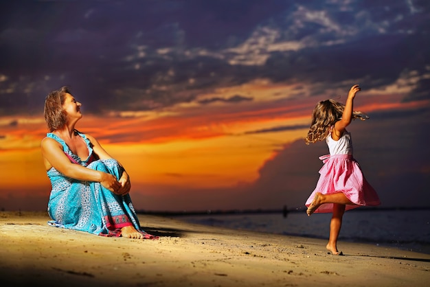 Madre e figlia in mare con il tramonto