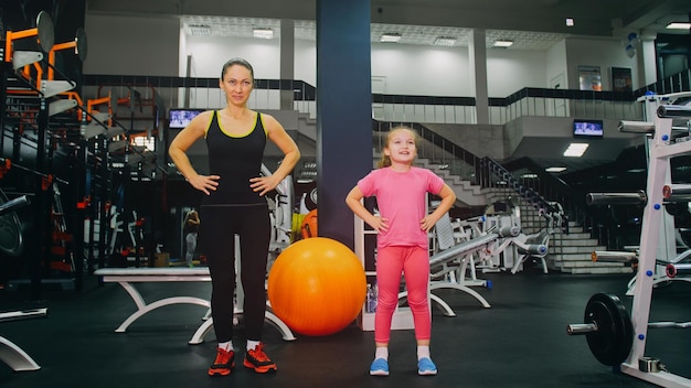 Madre e figlia in palestra la famiglia esegue esercizi fisici facendo esercizi di fitness stile di vita sano