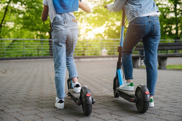 Madre e figlia in sella a scooter elettrici nel parco cittadino