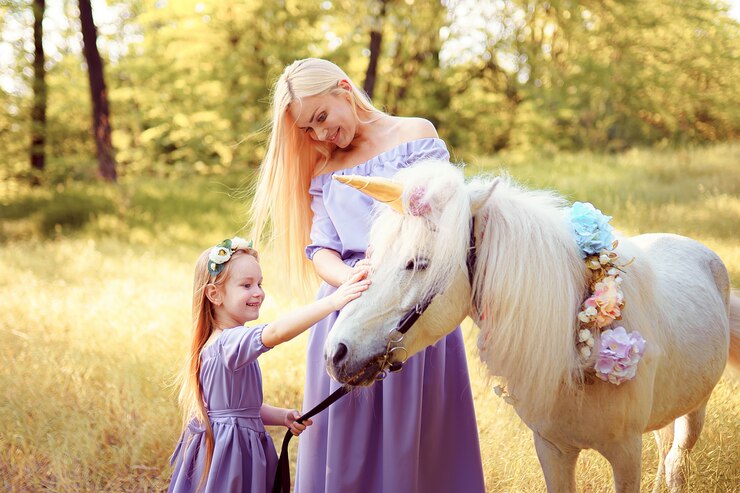 Foto madre e figlia in simili abiti di lavanda fanno accarezzare un unicorno