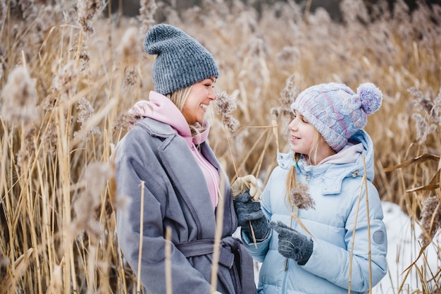 Madre e figlia in una passeggiata nella foresta, erba e neve, passeggiate invernali, foresta, campo, abiti invernali