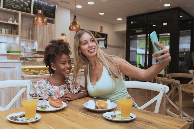 Madre e figlia interrazziali fanno una felice colazione in un ristorante