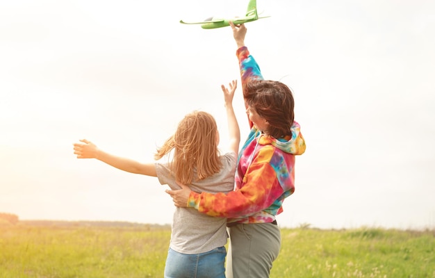 Madre e figlia lanciano un aereo giocattolo sul campo ragazza e donna che trascorrono del tempo in famiglia insieme a...