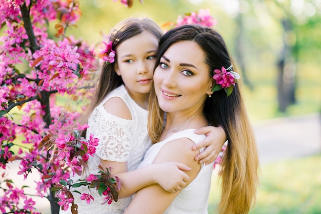 Madre e figlia nei roseti di fioritura di melo. Felice maternità Bellissimo ritratto di famiglia