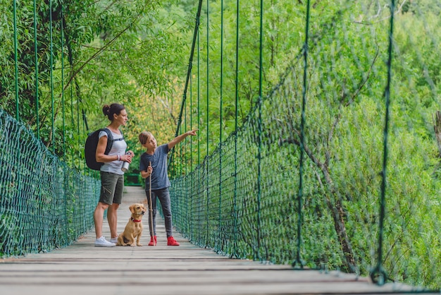 Madre e figlia nella foresta che camminano sopra il ponte di legno