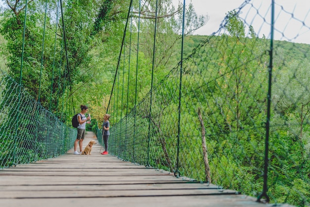 Madre e figlia nella foresta che camminano sopra il ponte di legno