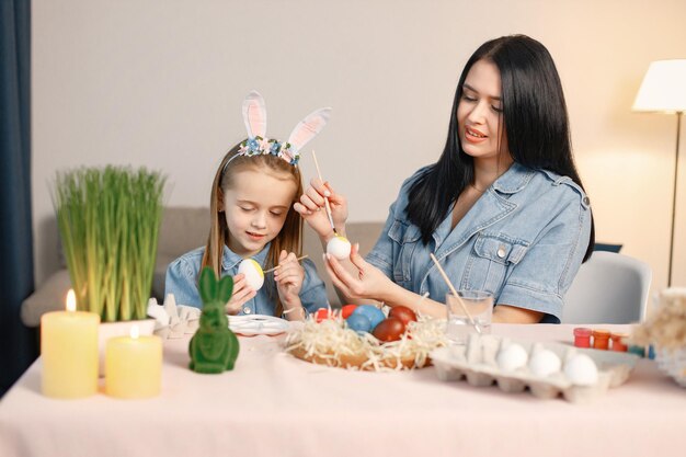 Madre e figlia nella moderna cucina leggera e dipingono insieme le uova di Pasqua