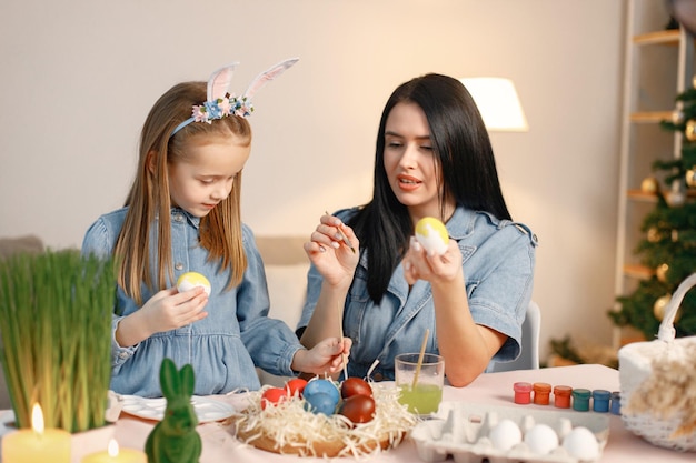 Madre e figlia nella moderna cucina leggera e dipingono insieme le uova di Pasqua