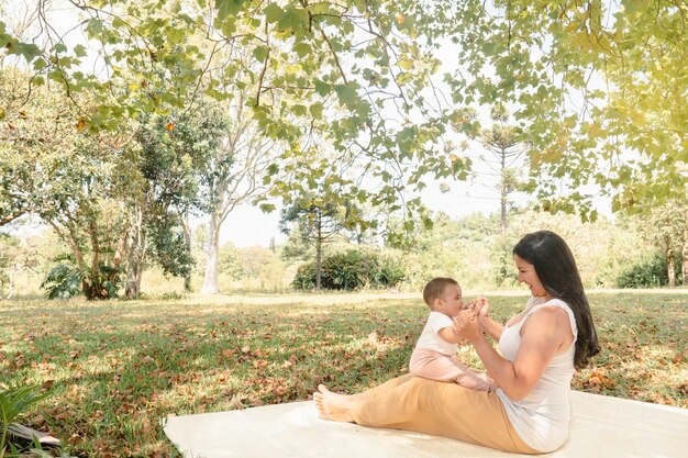 Madre e figlia seduta su una coperta in un parco in una giornata di sole