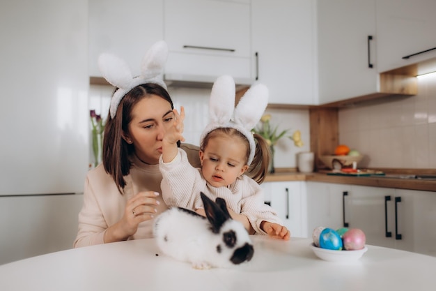 Madre e figlia si stanno preparando per la Pasqua abbracciandosi sorridendo trascorrendo del tempo insieme indossando orecchie da coniglio