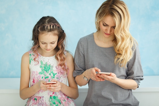 Madre e figlia sono sedute l'una accanto all'altra guardando nei loro telefoni e non parlano.