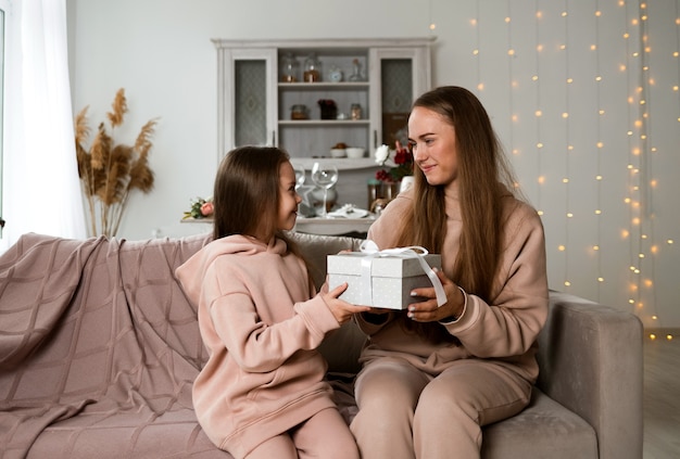 Madre e figlia sono sedute sul divano con una confezione regalo