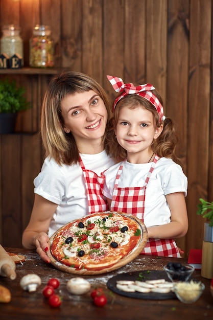 Madre e figlia sorridenti felici con pizza cotta