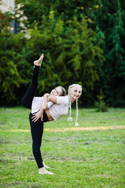 Madre e figlia sportive che si allungano sull'erba