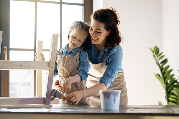 Madre e figlia stanno dipingendo uno sgabello di legno