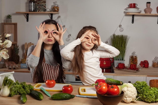 Madre e figlia stanno preparando un'insalata di verdure e si divertono in cucina.