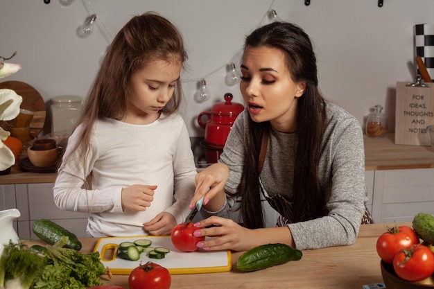 Madre e figlia stanno preparando un'insalata di verdure e si divertono in cucina.