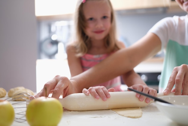 Madre e figlia stendono la pasta in cucina a casa primo piano