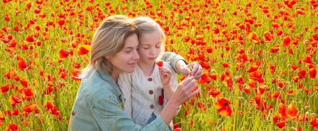 Madre e figlia sullo sfondo del campo di papaveri bandiera della famiglia di primavera bellissima bambina con y