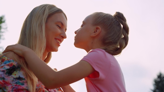 Madre e figlia sveglie che si guardano nel parco cittadino al tramonto