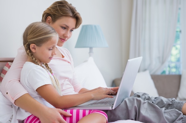 Madre e figlia usando il portatile a letto