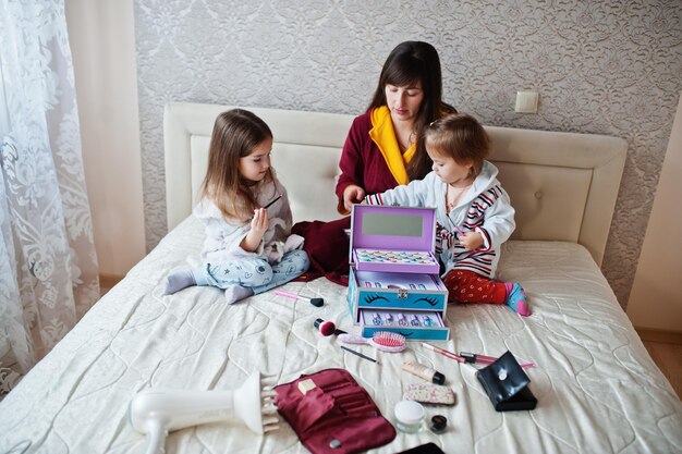 Madre e figlie che fanno il trucco sul letto in camera da letto.