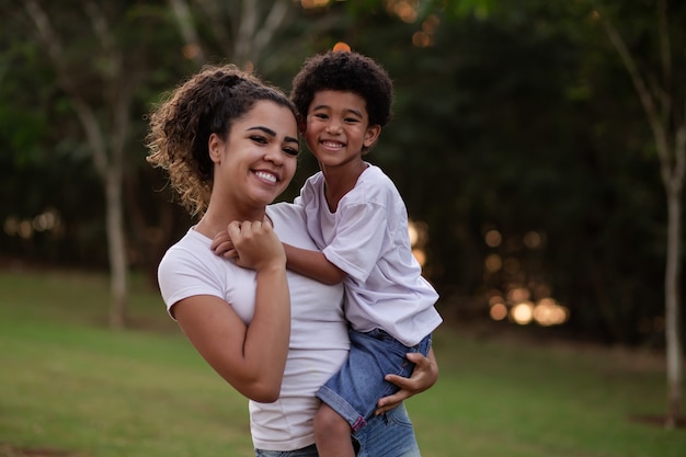 Madre e figlio afro nel parco sorridono alla telecamera