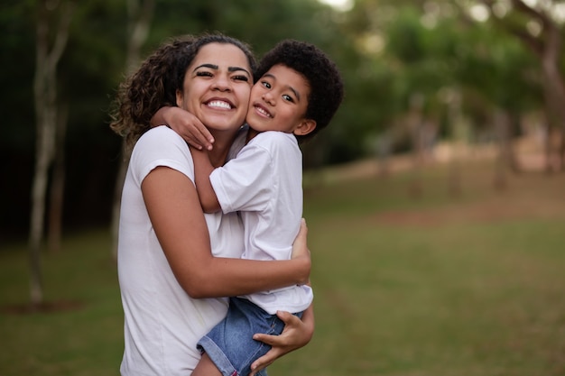 Madre e figlio afro nel parco sorridono alla telecamera