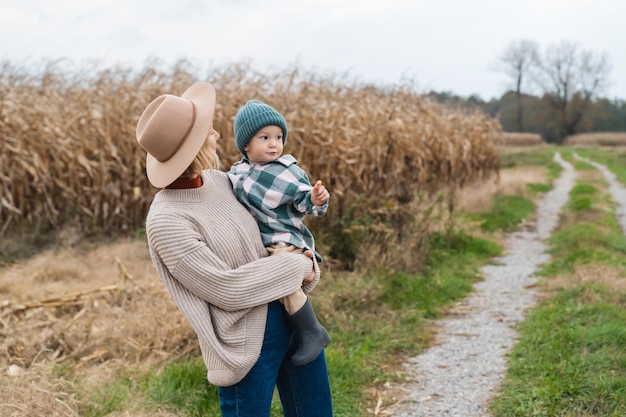 Madre e figlio camminano giocando insieme in un'area agricola Donna felice con bambino sulla strada nella natura Tradizioni familiari Concetto di stile di vita sostenibile legame familiare genitorialità naturale