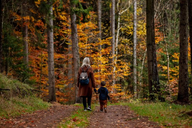 Madre e figlio camminano nella foresta in autunno