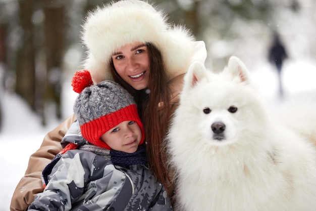 Madre e figlio che camminano con il cane Samoiedo bianco nella giornata invernale