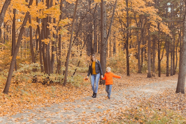 Madre e figlio che camminano nel parco autunnale e si godono la bellissima stagione della natura autunnale single