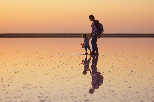 Madre e figlio che camminano su un sale e salamoia di un lago rosa, na