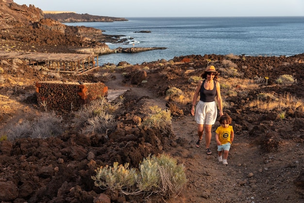 Madre e figlio che camminano su un sentiero al tramonto sulla spiaggia di Tacoron a El Hierro Isole Canarie