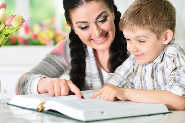 Madre e figlio che fanno i compiti insieme leggendo un libro