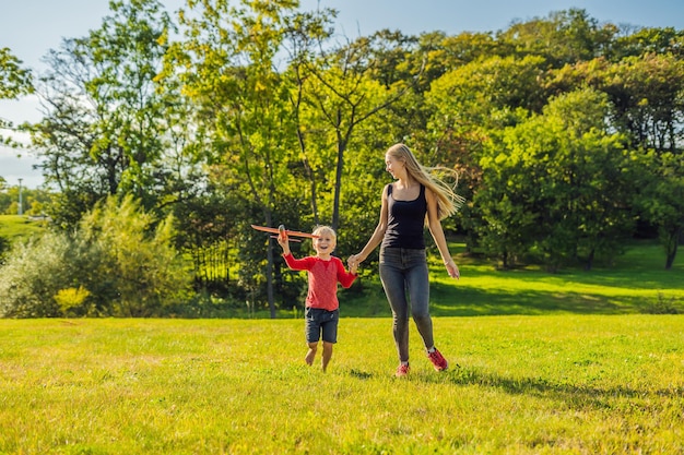 Madre e figlio che giocano con un aeroplano giocattolo di grandi dimensioni nel parco