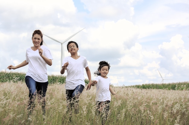 Madre e figlio che giocano in campo con un'enorme turbina eolica sullo sfondo