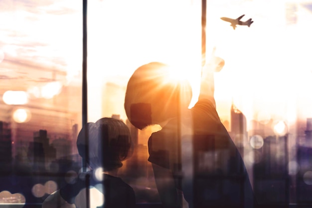 Madre e figlio che puntano all'aeroplano nel cielo del tramonto