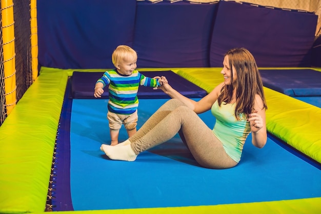 Madre e figlio che saltano su un trampolino nel parco fitness e fanno esercizio al chiuso