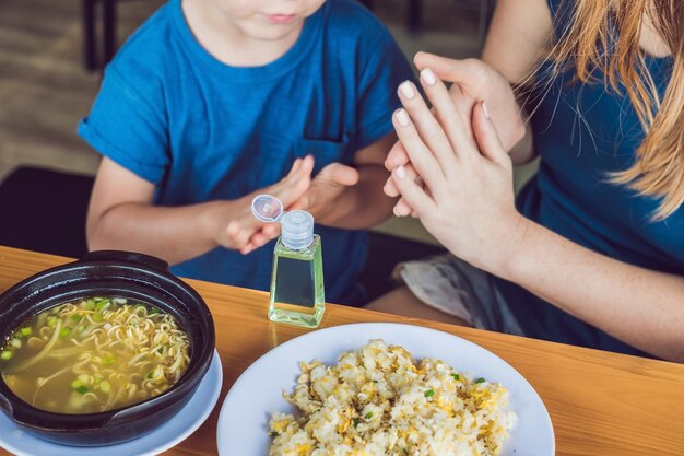 Madre e figlio che usano il gel igienizzante per le mani nella caffetteria.