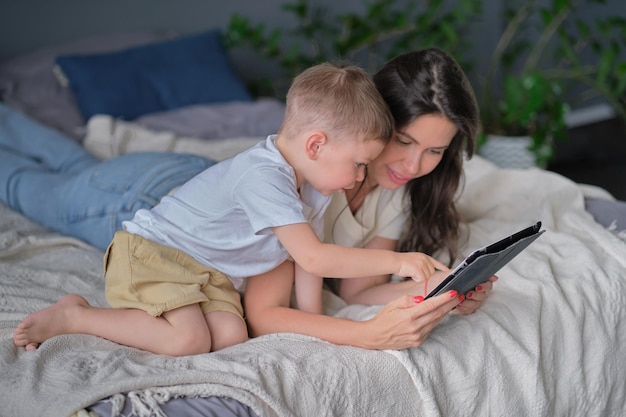Madre e figlio con tablet a casa Madre che mostra i contenuti multimediali in linea a suo figlio in un tablet nel soggiorno all'interno di una casa